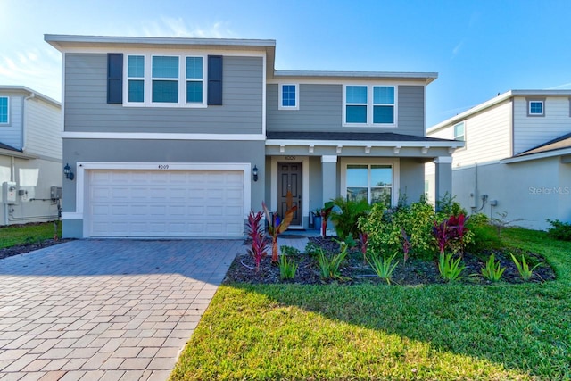 view of front facade with a front yard, decorative driveway, an attached garage, and stucco siding