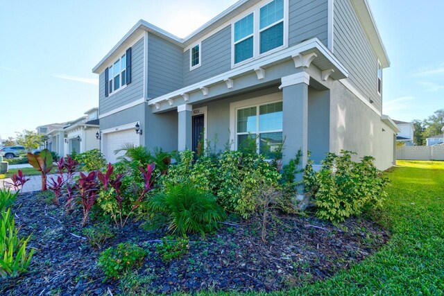 4009 Winding Meadows St, Apopka, FL 32712 - view of side of property with an attached garage, a lawn, stucco siding, and fence