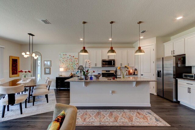 4009 Winding Meadows St, Apopka, FL 32712 - kitchen featuring light stone counters, stainless steel appliances, white cabinets, visible vents, and dark wood-type flooring
