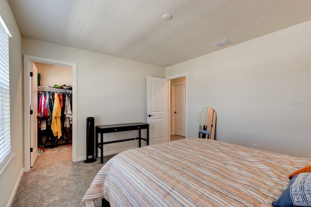 carpeted bedroom with a walk in closet, multiple windows, a closet, and a textured ceiling