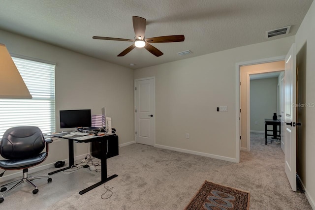 carpeted home office featuring a textured ceiling and ceiling fan