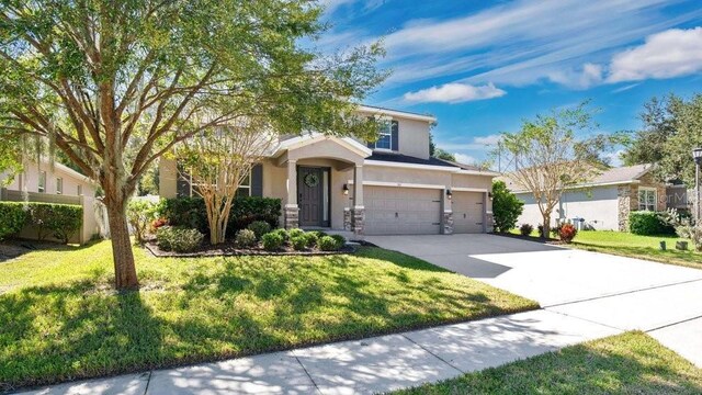 521 Morgan Wood Dr, Deland, FL 32724 - view of front of house with driveway, stucco siding, a front lawn, and a garage