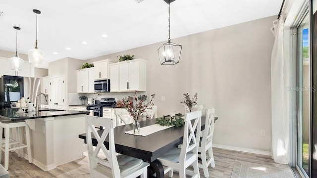 dining area featuring light hardwood / wood-style flooring, sink, and an inviting chandelier