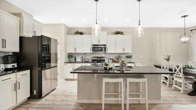 kitchen with light hardwood / wood-style flooring, tasteful backsplash, stainless steel appliances, and hanging light fixtures