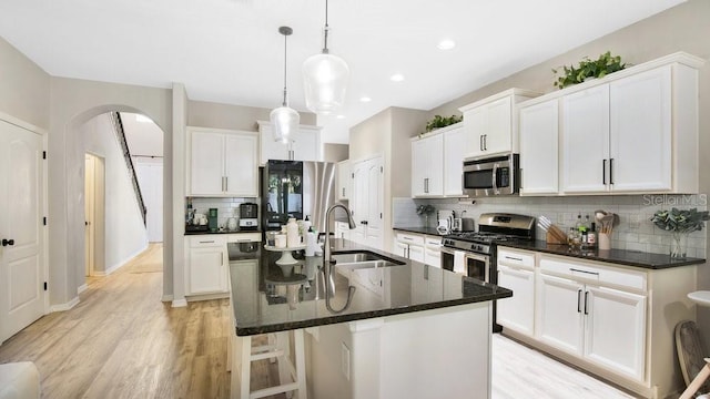 kitchen with sink, appliances with stainless steel finishes, tasteful backsplash, and an island with sink