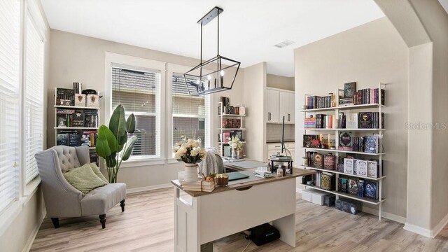 home office with a chandelier and light hardwood / wood-style flooring