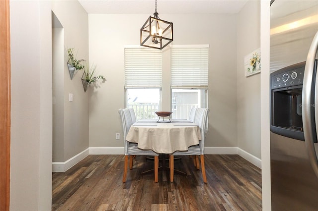 dining area with dark hardwood / wood-style floors and an inviting chandelier