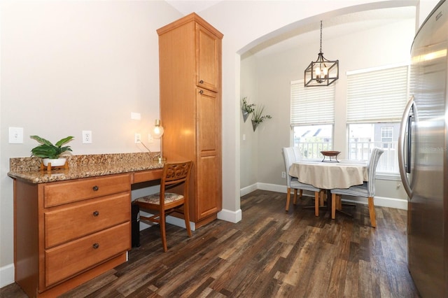 dining space with built in desk, dark wood-type flooring, and an inviting chandelier