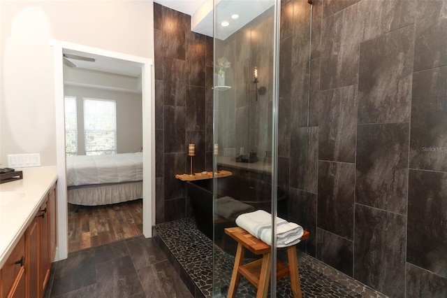 bathroom with vanity, a tile shower, hardwood / wood-style flooring, and ceiling fan