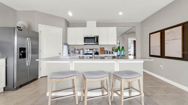 kitchen featuring a kitchen island with sink, stainless steel appliances, white cabinets, and light tile patterned floors