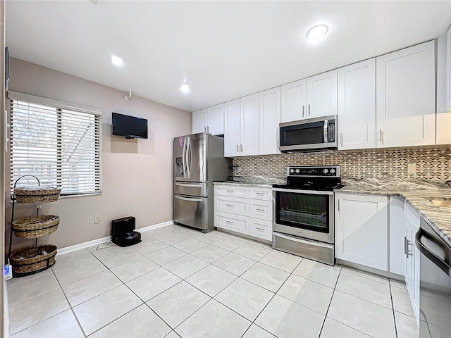 kitchen with appliances with stainless steel finishes, white cabinetry, tasteful backsplash, and light stone counters