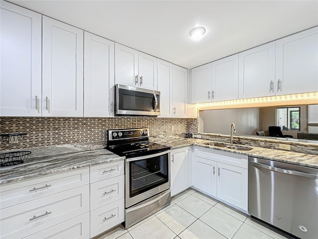 kitchen with light tile patterned floors, appliances with stainless steel finishes, sink, and white cabinets