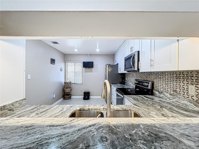 kitchen featuring stainless steel appliances, sink, white cabinetry, light stone counters, and tasteful backsplash