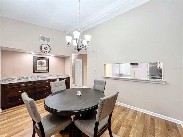 dining room featuring light hardwood / wood-style floors, a textured ceiling, and an inviting chandelier