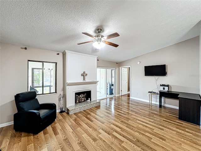 living room with vaulted ceiling, a textured ceiling, light hardwood / wood-style flooring, and ceiling fan