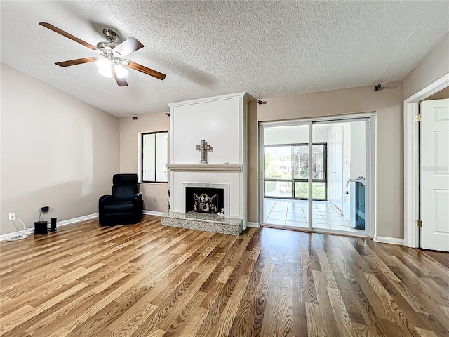 unfurnished living room with ceiling fan, a textured ceiling, a wealth of natural light, and light wood-type flooring