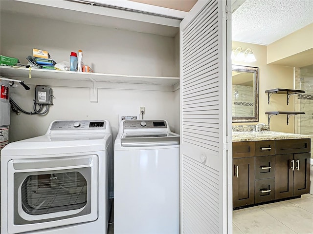 clothes washing area with independent washer and dryer, a textured ceiling, and light tile patterned flooring