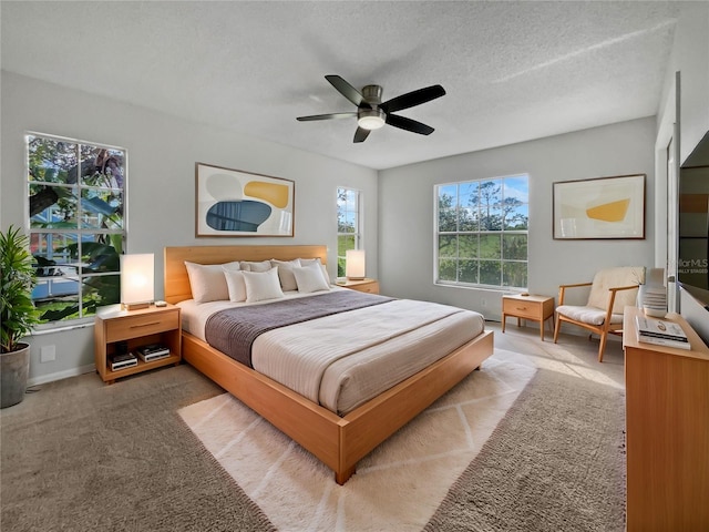 bedroom featuring ceiling fan, a textured ceiling, and light colored carpet