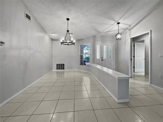 unfurnished dining area with an inviting chandelier, a textured ceiling, and light tile patterned floors