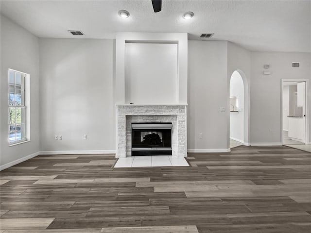 unfurnished living room with a textured ceiling, a fireplace, and dark hardwood / wood-style flooring