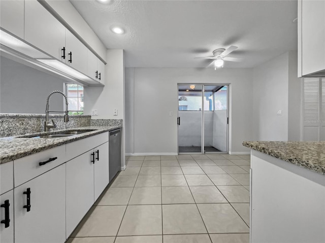 kitchen featuring light stone countertops, sink, white cabinetry, stainless steel dishwasher, and light tile patterned floors