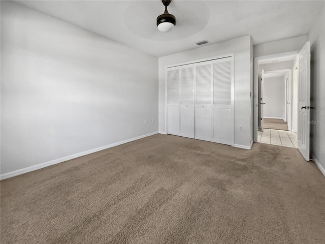 unfurnished bedroom with a closet, ceiling fan, and light carpet