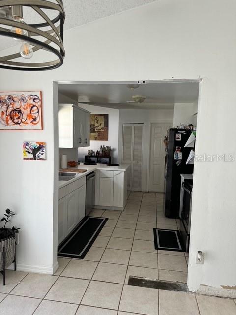 kitchen with dishwasher, black fridge, a textured ceiling, and light tile patterned floors