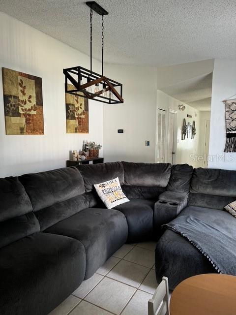 living room featuring a textured ceiling, light tile patterned flooring, and an inviting chandelier