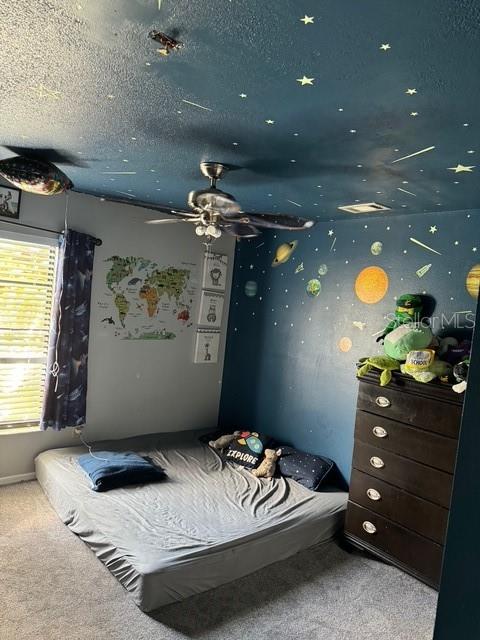 carpeted bedroom featuring a textured ceiling and ceiling fan