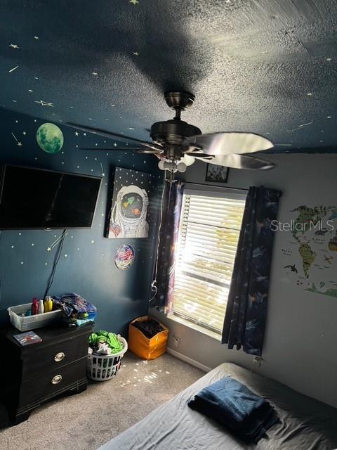 carpeted bedroom featuring a textured ceiling and ceiling fan