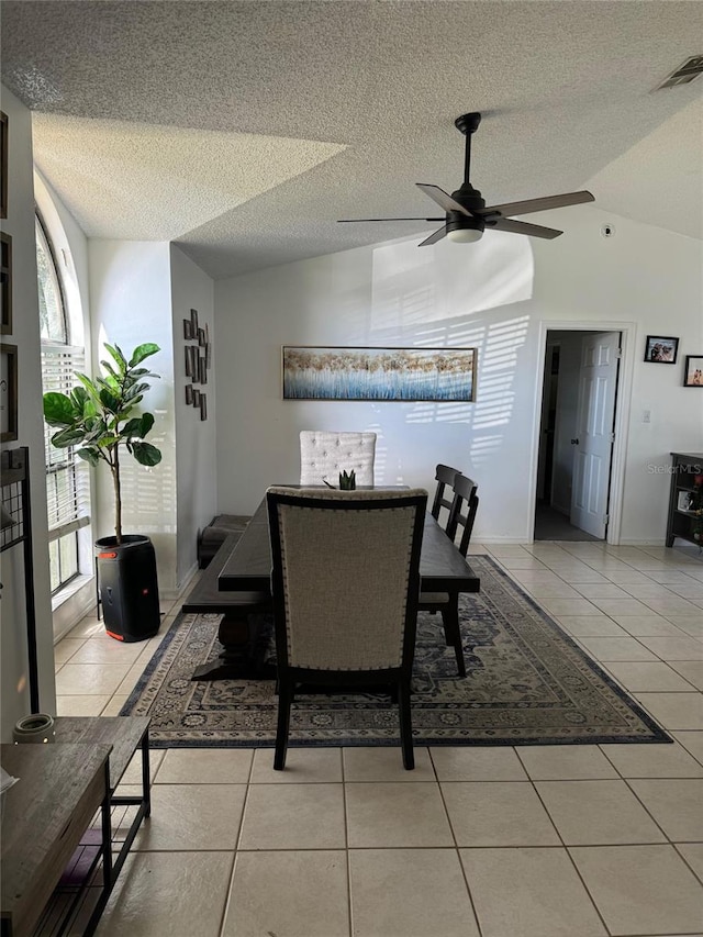 dining space featuring vaulted ceiling, a textured ceiling, light tile patterned floors, and ceiling fan