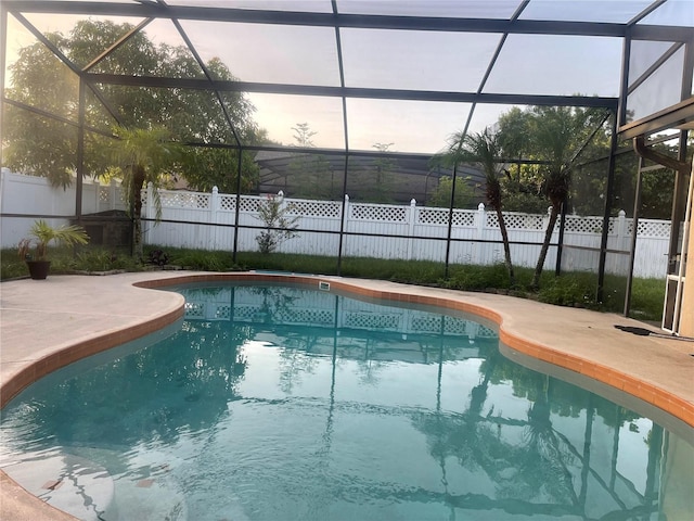 pool at dusk with a patio and glass enclosure