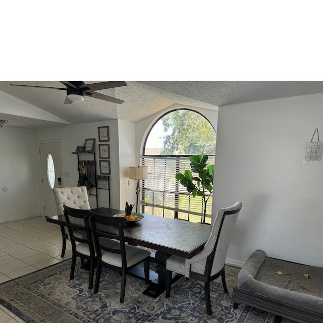 tiled dining space with a textured ceiling and ceiling fan