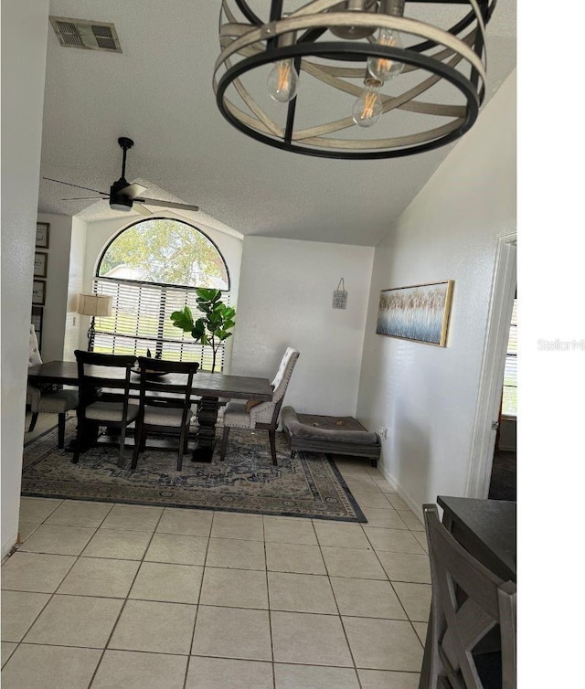 dining room featuring vaulted ceiling, a textured ceiling, ceiling fan with notable chandelier, and light tile patterned floors