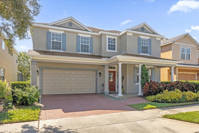 view of front facade featuring a garage, decorative driveway, and stucco siding