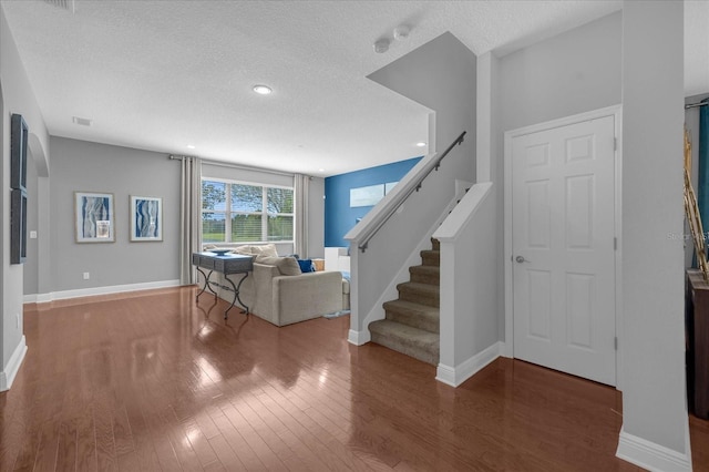 unfurnished living room with a textured ceiling and dark hardwood / wood-style flooring