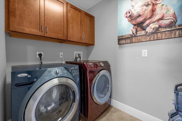 laundry room with light tile patterned flooring, washing machine and clothes dryer, and cabinets