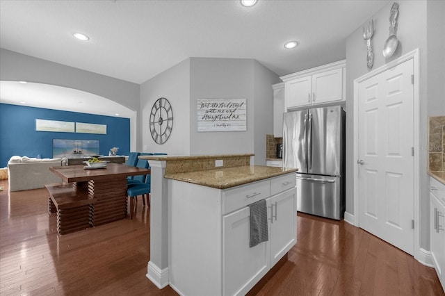 kitchen with light stone counters, recessed lighting, dark wood-type flooring, freestanding refrigerator, and white cabinets