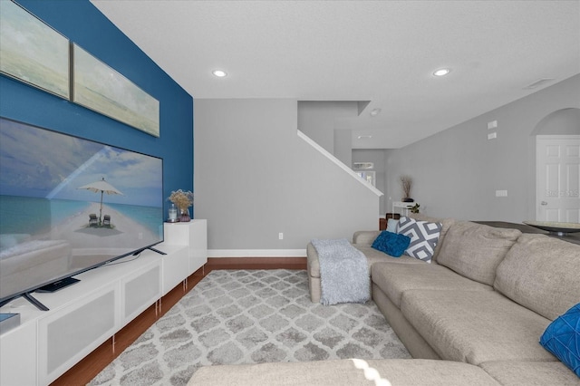 living room featuring baseboards, arched walkways, wood finished floors, and recessed lighting