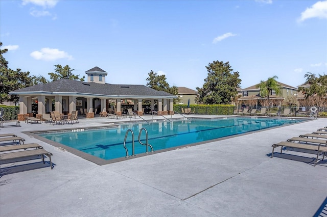 community pool with a patio area and fence