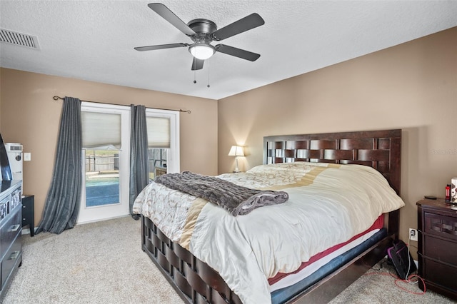 bedroom with a textured ceiling, light colored carpet, and ceiling fan