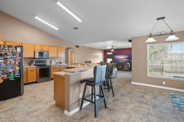 kitchen with stainless steel appliances, vaulted ceiling, a kitchen bar, decorative light fixtures, and ceiling fan