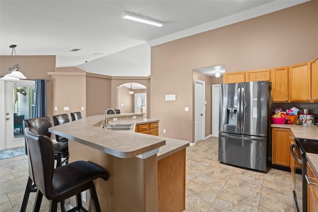 kitchen featuring hanging light fixtures, stainless steel fridge with ice dispenser, a kitchen island with sink, a kitchen bar, and black electric range