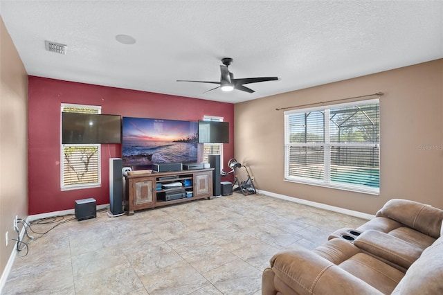 living room featuring ceiling fan and a textured ceiling