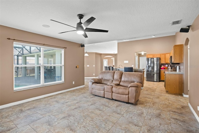 living room featuring ceiling fan and a textured ceiling