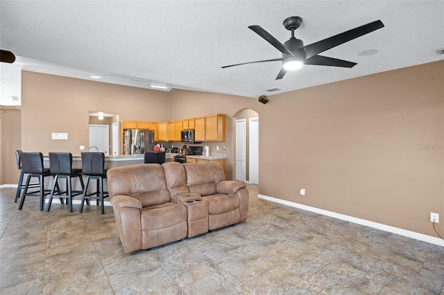 living room featuring ceiling fan, a textured ceiling, and lofted ceiling