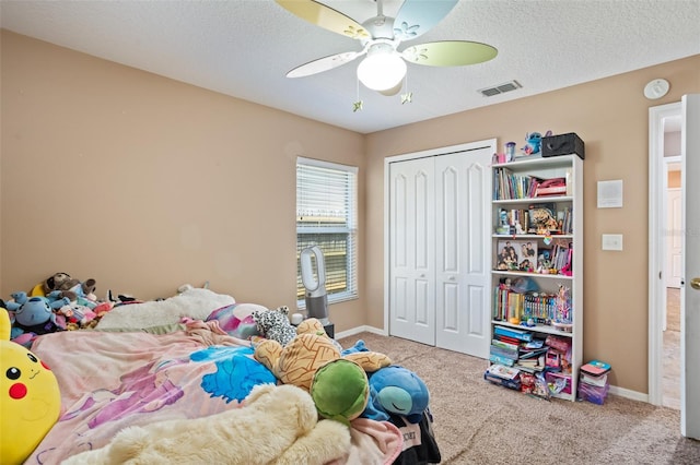 carpeted bedroom with a closet, ceiling fan, and a textured ceiling