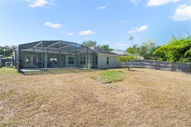 rear view of house with glass enclosure and a lawn