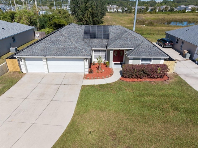 ranch-style house with a water view, solar panels, a front lawn, and a garage