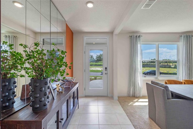 tiled entrance foyer featuring beam ceiling and a textured ceiling